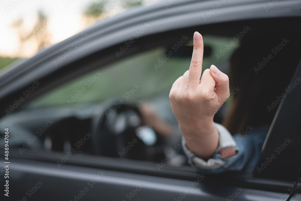 Angry woman driver shows an obscene gesture a middle finger through the window.