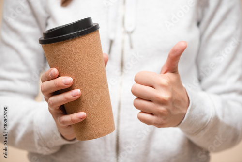 Coffee cup in the hand and thumbs up gesture close up. Best coffee concept.
