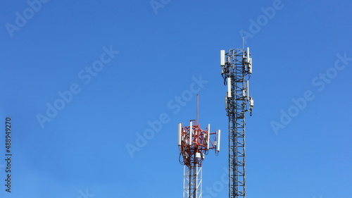 Twin Tower Cellular Base Station. A base station equipped with 4G and 5G cellular wireless communication technology that transmits radio waves to a mobile phone with a clear sky background. 