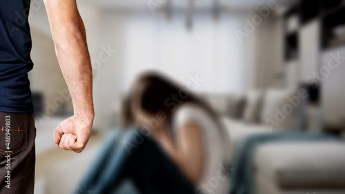 Man stands with fist clenched against background of crying sad woman