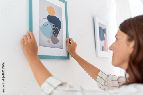 Obraz na plátne home improvement, decoration and people concept - woman hanging picture in frame