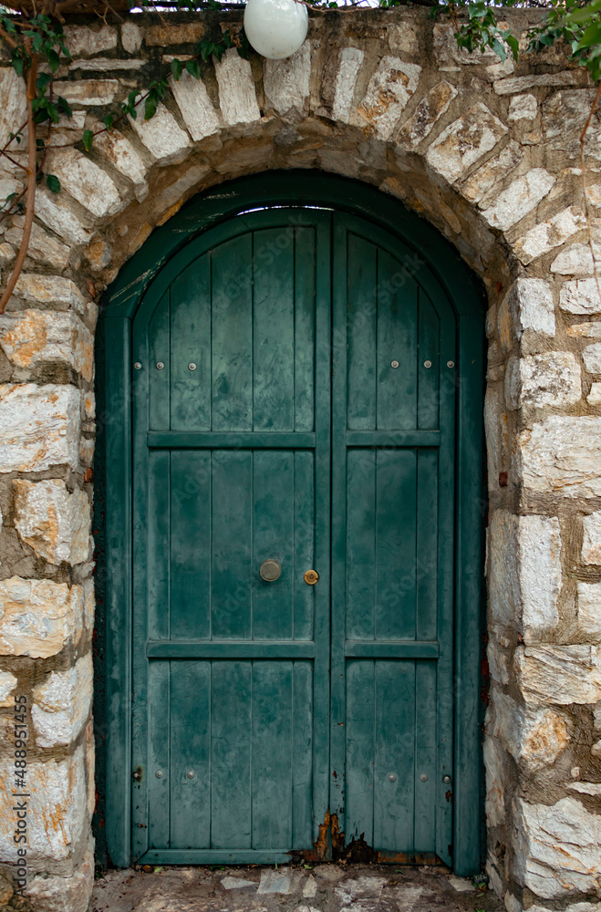 A wooden old green door of stone house. Very symmetrical photo. Vintage architectural elements. A wooden old green door of stone house. Very symmetrical photo. Vintage architectural elements.