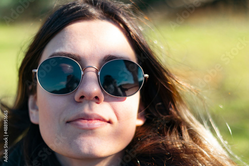 Young woman is enjoying the fresh air. She has sun glasses. Happiness and finding peace concept. Sunlights. Close up photo.
