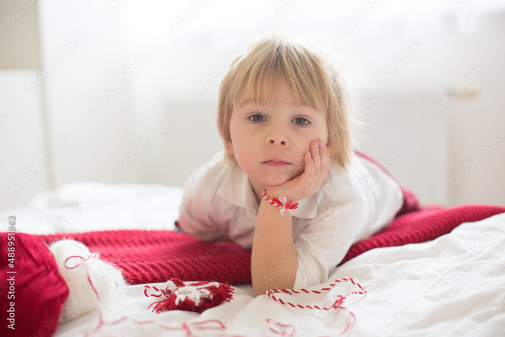 Cute child, blond boy, playing with white and red bracelet Cute child, blond boy, playing with white and red bracelet