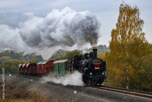 historic steam freight train passes through the autumn landscape