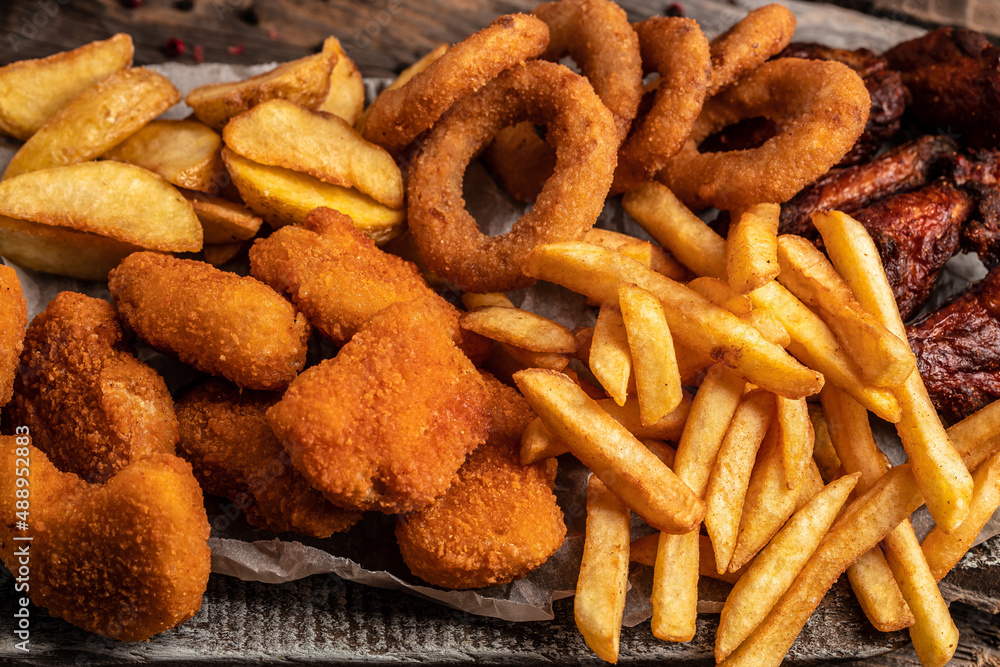 take away fast food products fried chicken with french fries and nuggets meal, junk food and unhealthy food on a wooden board. banner, menu, recipe place for text take away fast food products fried chicken with french fries and nuggets meal, junk food and unhealthy food on a wooden board. banner, menu, recipe place for text