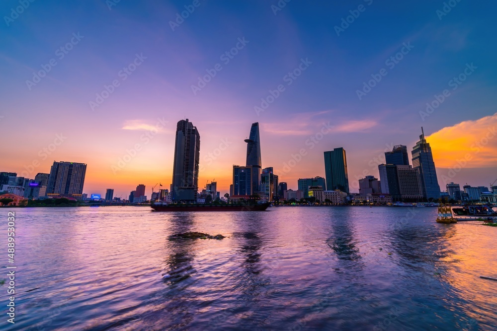 View of Bitexco Financial Tower building, buildings, roads, Thu Thiem bridge and Saigon river in Ho Chi Minh city in sunset.