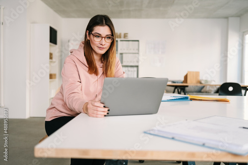 Confident beautiful female freelancer using laptop working at home office