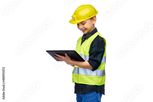 building, construction and profession concept - happy smiling little boy in protective helmet and safety vest with tablet pc computer over white background