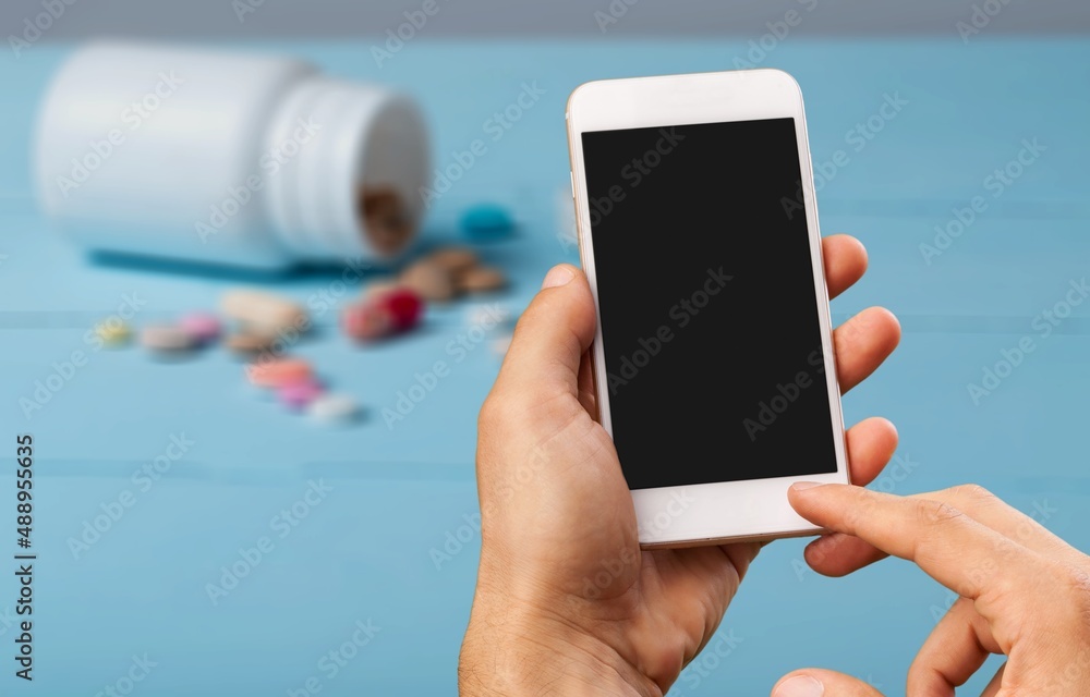 Patient hand using smartphone. Pharmaceutical use. Drugs. Pills. Prospectus. Using Smarthphone Patient hand using smartphone. Pharmaceutical use. Drugs. Pills. Prospectus. Using Smarthphone