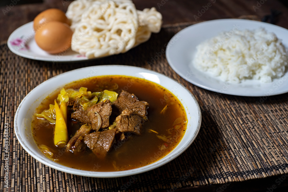 Rawon is a strong rich tasting traditional Indonesian beef black soup served From east java with rice, egg and krupuk on background Rawon is a strong rich tasting traditional Indonesian beef black soup served From east java with rice, egg and krupuk on background
