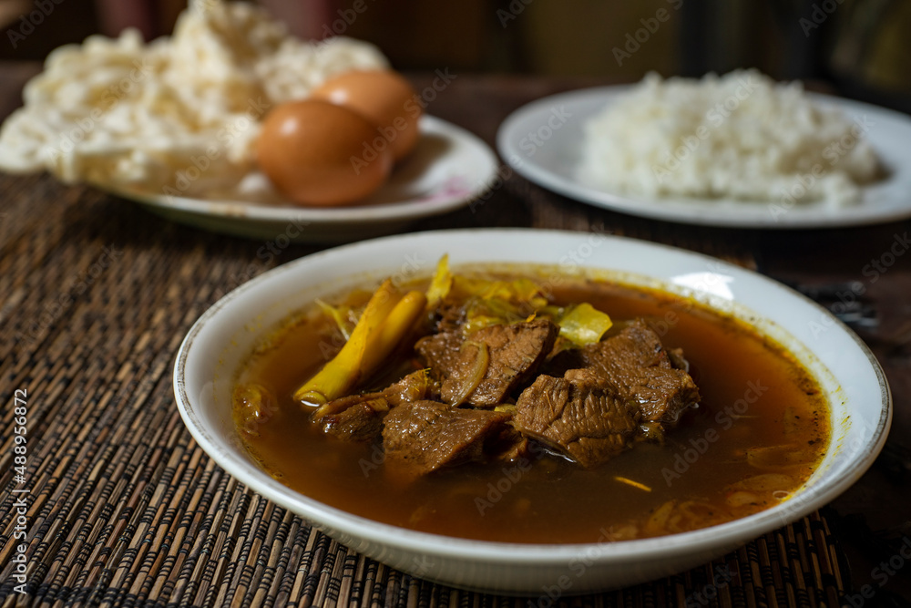 Rawon is a strong rich tasting traditional Indonesian beef black soup served From east java with rice, egg and krupuk on background Rawon is a strong rich tasting traditional Indonesian beef black soup served From east java with rice, egg and krupuk on background