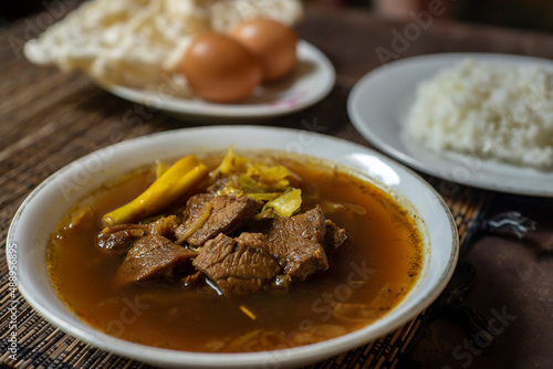 Rawon is a strong rich tasting traditional Indonesian beef black soup served From east java with rice, egg and krupuk on background