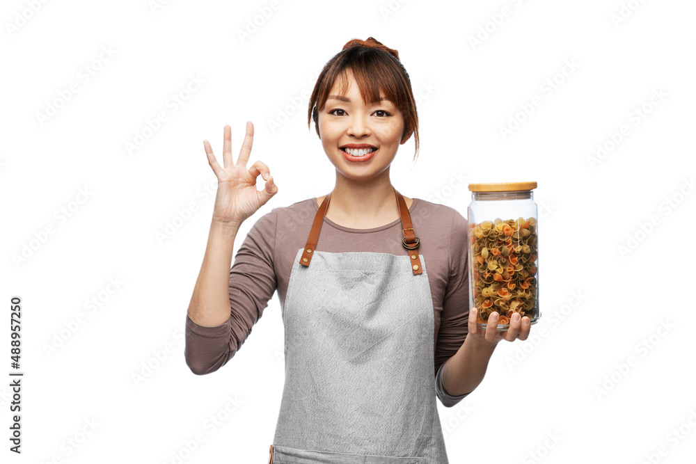 cooking, culinary and people concept - happy smiling woman in apron holding jar with pasta showing ok hand sign over white background cooking, culinary and people concept - happy smiling woman in apron holding jar with pasta showing ok hand sign over white background