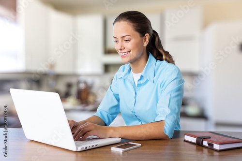 Young happy woman student learning looking at laptop computer watching online webinar