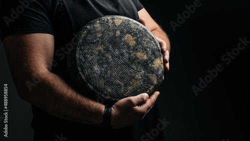 cheesemaker holds a cheese head, Dutch cheese. dairy products on a dark background. banner, menu, recipe place for text photo