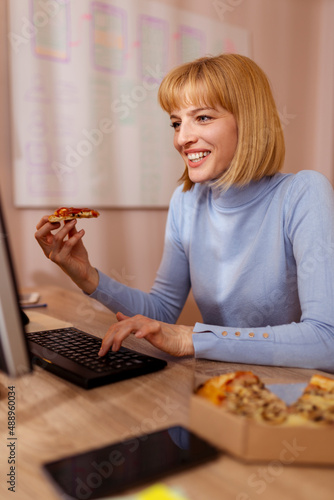 Woman working in an office eating pizza