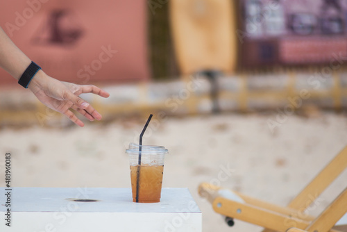 Close-up of a man's hand reaching for a cup of coffee placed on a white table.
