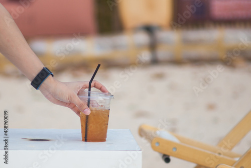 Close-up of a man's hand reaching for a cup of coffee placed on a white table.