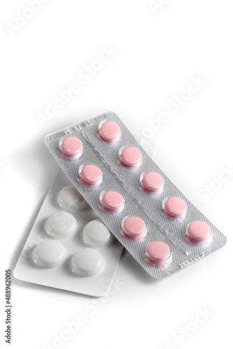 Close-up of a couple white pills or capsules on isolated white background.