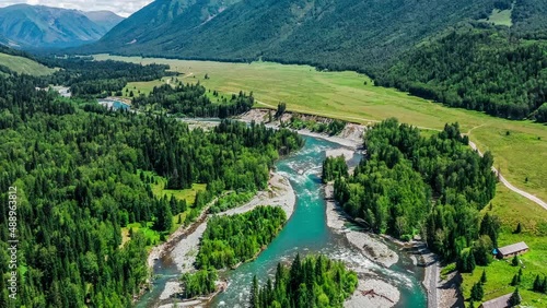 Aerial footage of river and green forest with mountain natural landscape in Xinjiang, China. Green nature landscape in summer season.
