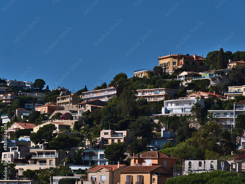 View of luxury apartment buildings and holidays home on the slope of a hill above small town Villefranche-sur-Mer at the French Riviera.