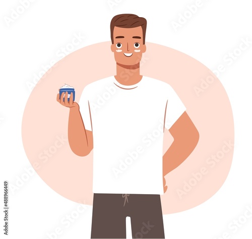 Skincare routine concept for man. Happy young guy in towel holding a face cream in hand.