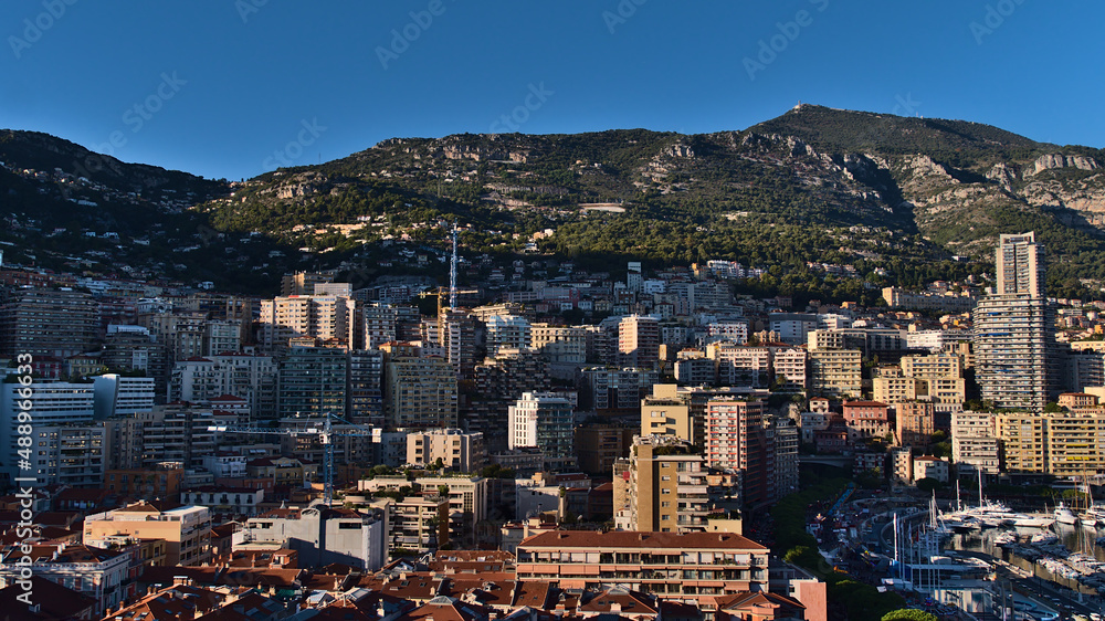 Beautiful panoramic view of the downtown of Monaco at the mediterranean coast in the afternoon sunlight with dense development surrounded by hills.