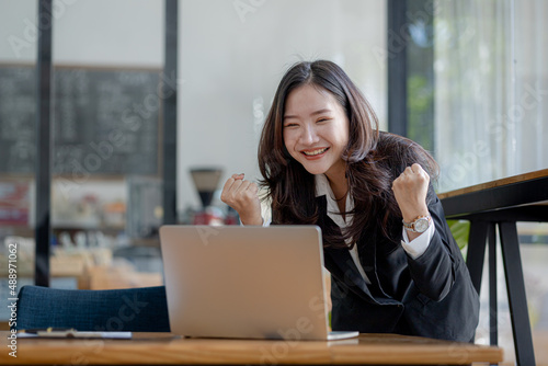 Woman gesturing and looks at laptop screen, businesswoman checking company monthly sales and pretending to be happy as sales meet planned targets according to policy. Sales management concept.