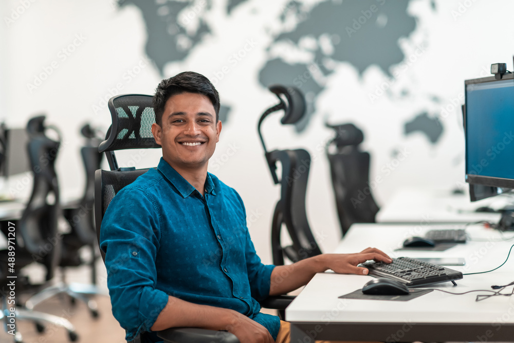 Casual business man working on desktop computer in modern open plan startup office interior. Selective focus Casual business man working on desktop computer in modern open plan startup office interior. Selective focus