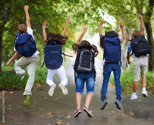 Fototapeta Naklejka Na Ścianę i Meble -  Spring break. Rear view of excited schoolchildren jumping in a row.