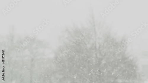 Heavy falling snow in slow motion 4K with big snowflakes falling down from the cloudy sky in winter.