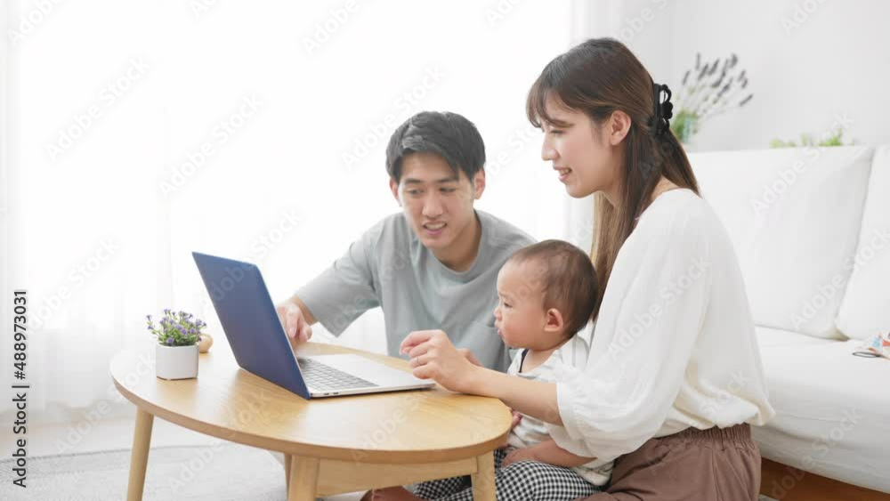 赤ちゃんにノートパソコンを見せる両親