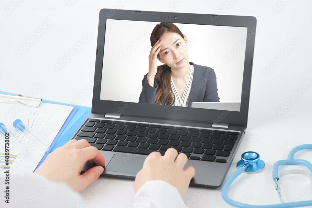 職場でオンライン診療を受ける女性 ノートパソコンのモニター越し クリニックもしくは病院 遠隔医療 職場でオンライン診療を受ける女性 ノートパソコンのモニター越し クリニックもしくは病院 遠隔医療