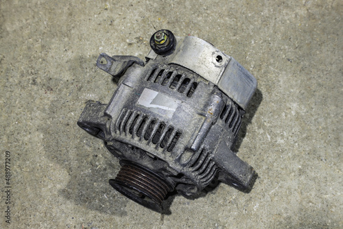 Old dirty car generator on a gray background close-up. Car parts