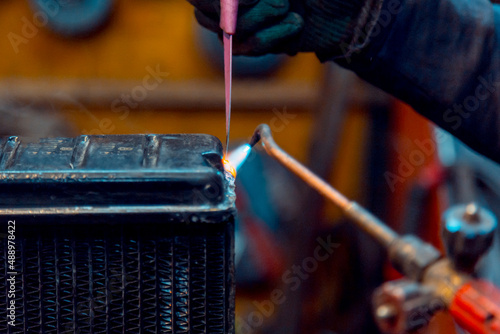 Welder solders copper car radiator with gas torch