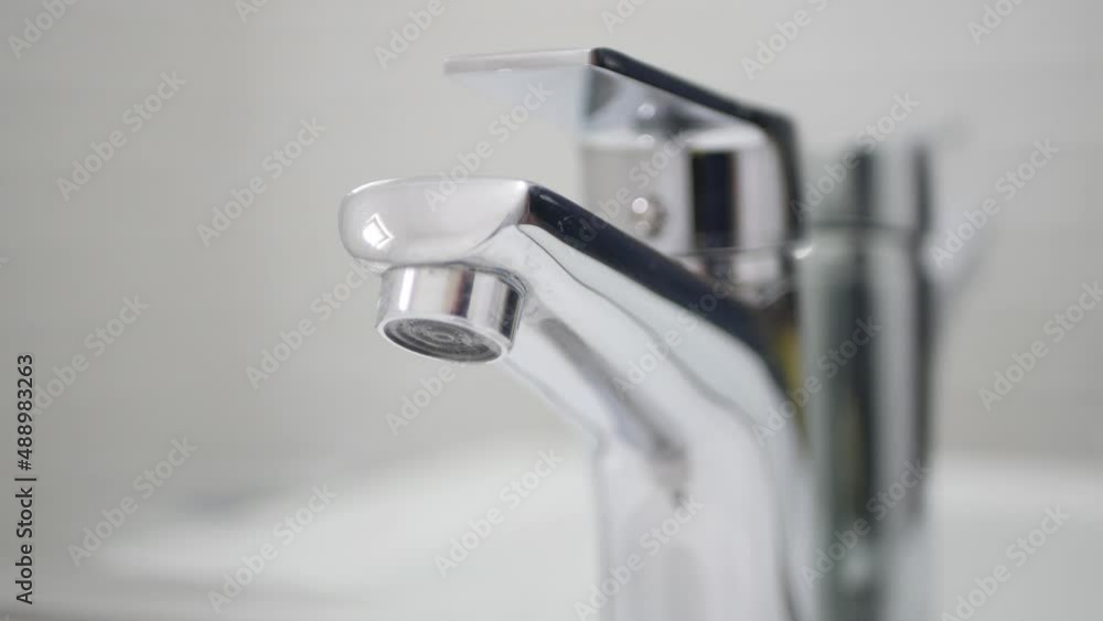 Adult Wearing Protective Household Gloves in Hands Closing the Sink Tap from the Bathroom. Adult Wearing Protective Household Gloves in Hands Closing the Sink Tap from the Bathroom.