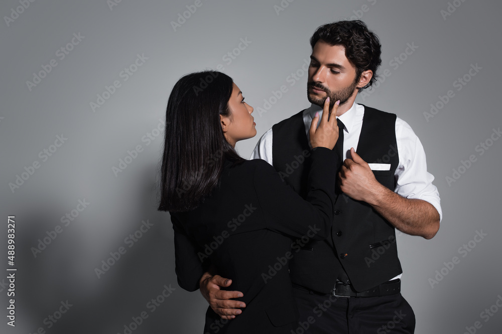 sensual asian woman touching face of stylish man on grey background sensual asian woman touching face of stylish man on grey background