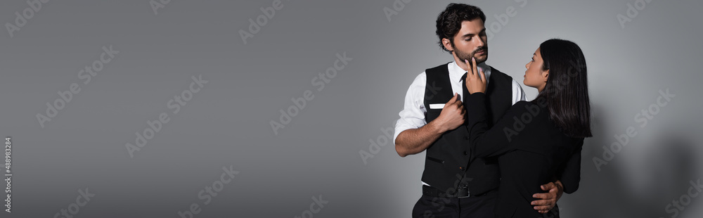 back view of asian woman touching face of elegant man on grey background, banner