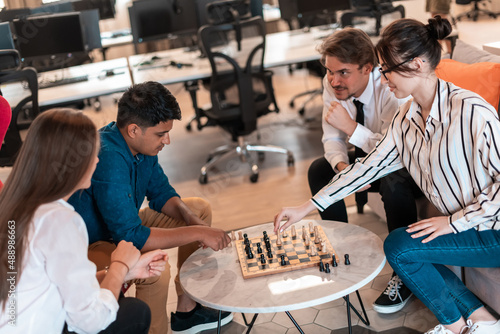 Multiethnic group of business people playing chess while having a break in relaxation area at modern startup office