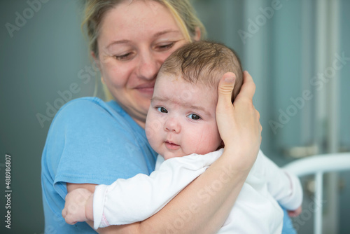 Mom carefully holds her little daughter in her arms.