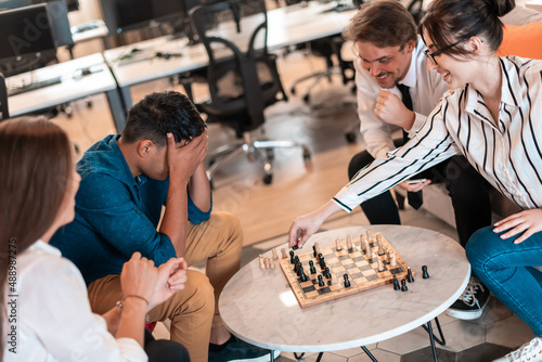 Multiethnic group of business people playing chess while having a break in relaxation area at modern startup office © .shock