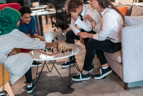 Multiethnic group of business people playing chess while having a break in relaxation area at modern startup office