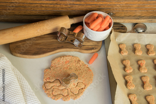 Making homemade healthy carrot dog treats. Dough  with cookie cutters.   photo