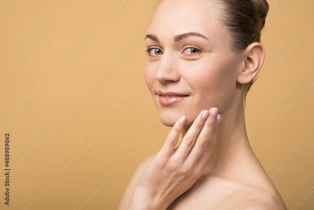 Happy caucasian girl with beautiful face touching healthy facial skin isolated on beige studio background. Skin care concept. Happy caucasian girl with beautiful face touching healthy facial skin isolated on beige studio background. Skin care concept.