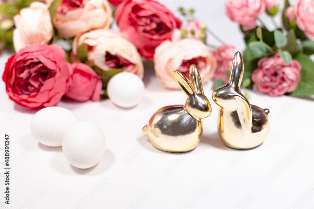 two golden rabbits behind white background with flowers two golden rabbits behind white background with flowers
