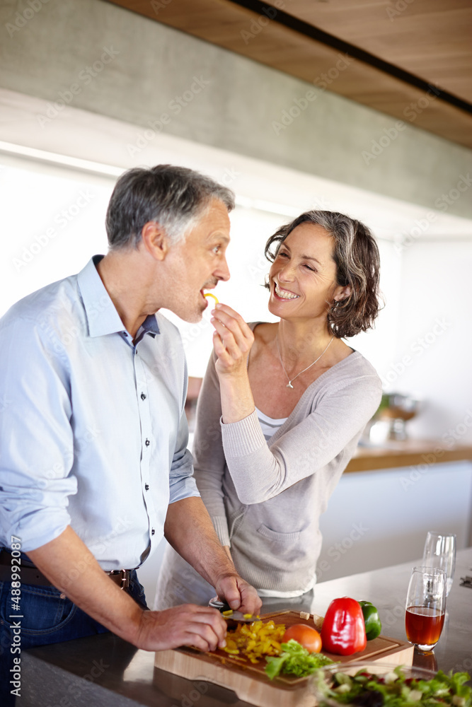 But its not cooked yet. A cropped shot of a woman feeding her husband a slice of yellow pepper.