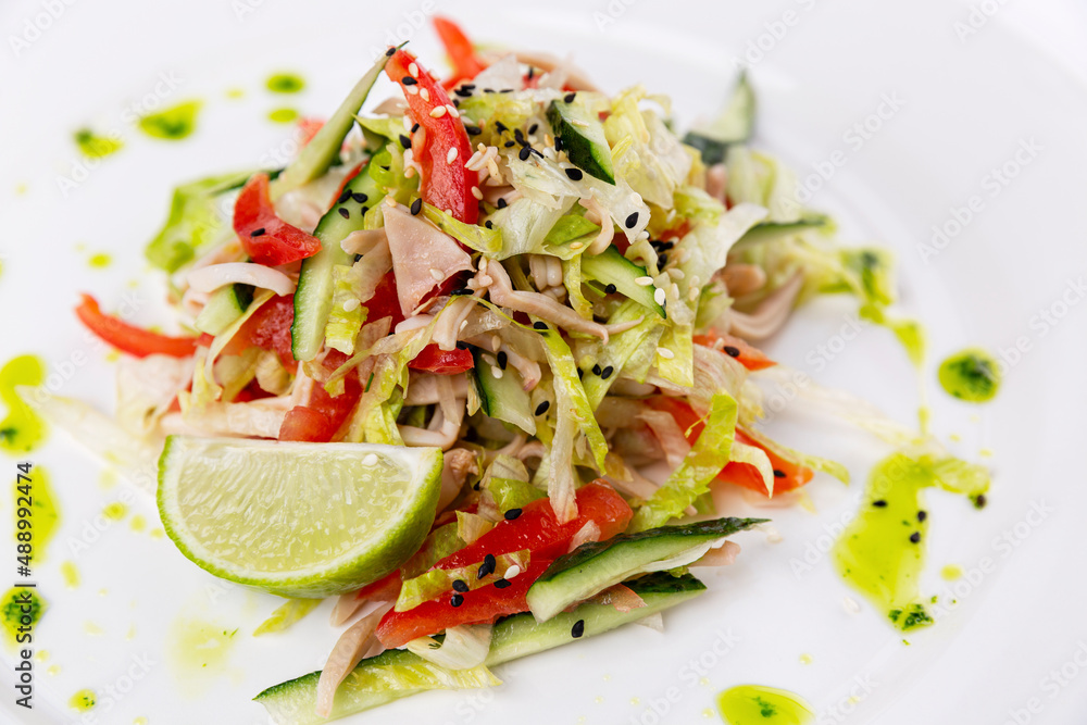 Fresh cabbage salad with ham on a white plate. Vitamin snack and healthy food. Close-up. Fresh cabbage salad with ham on a white plate. Vitamin snack and healthy food. Close-up.