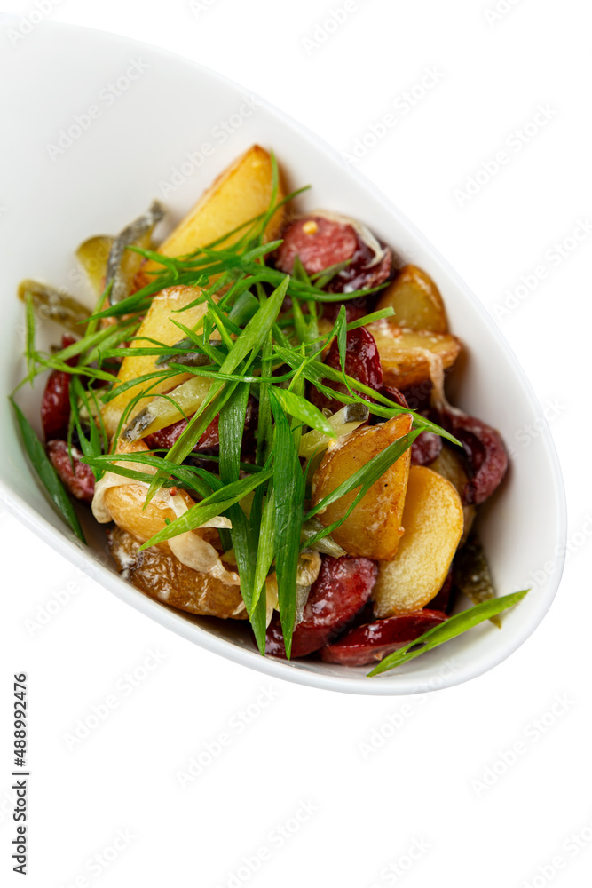 Potato salad with smoked sausages and green onions. Isolated on white background. Vertical. Potato salad with smoked sausages and green onions. Isolated on white background. Vertical.