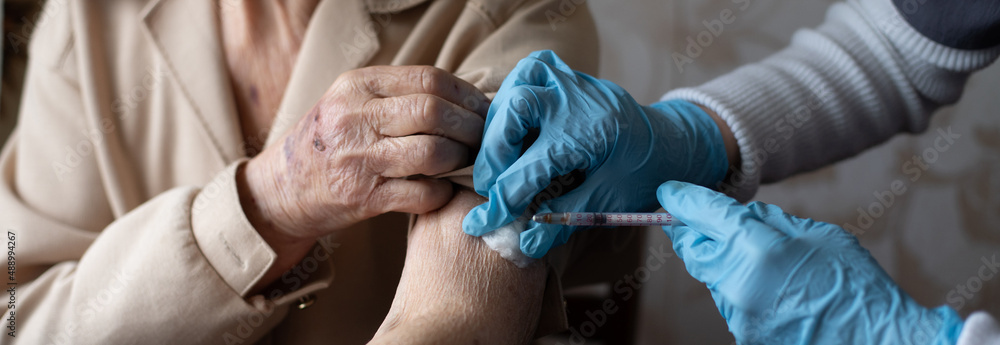 Nurse making vaccine injection to elderly patient - obrazy, fototapety, plakaty 